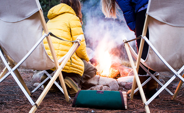 A Firewood Carrier beside a stone circle campfire.